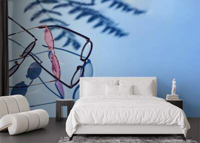 Different glasses with palm tree shadows on a blue background Wall mural