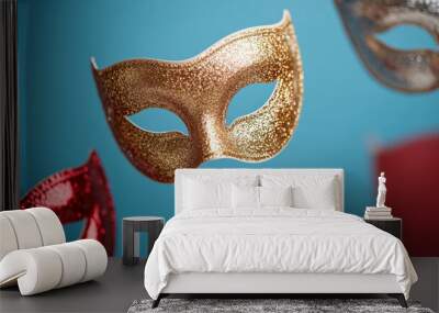 Festive masquerade masks in gold and silver floating against a gradient from sapphire blue to crimson  Wall mural