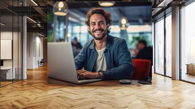 Portrait of attractive smiling man sitting in office and looking at camera.. Wall mural