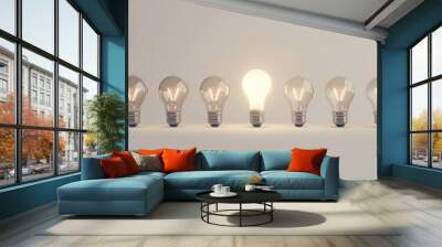 A row of light bulbs, with one bulb glowing brightly in the center, symbolizing innovation and ideas.  Wall mural