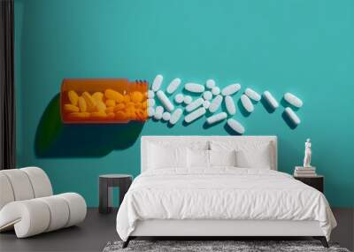 White pills spilling out of an orange and white pill bottle on a teal background.  Wall mural