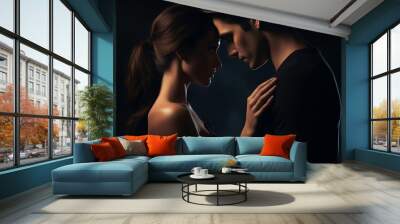 : A dramatic studio shot capturing a young couple, their hands entwined, gazing into each other's eyes, with the dark background accentuating the warmth and sincerity of their connection. Wall mural