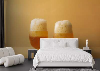 Two glasses filled with frothy, golden beer are captured against a warm, earthy background, invoking a sense of refreshment and relaxation. Wall mural