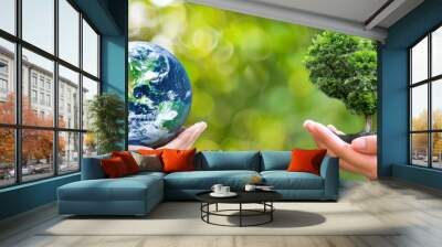 Two hands, each holding an object; one with a globe and the other with a heart-shaped tree, symbolizing global environmental care and harmony with nature. Wall mural