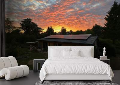 An idyllic scene with a modern house and blue solar panels on the roof at the end of the day, as the sun sinks below the horizon. Wall mural