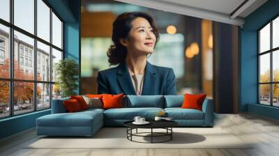 Happy proud prosperous mid aged mature professional Asian business woman ceo executive wearing suit standing in office arms crossed looking away thinking of success, leadership, side profile view. Wall mural