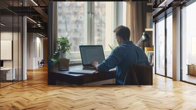 Man, typing in home office and laptop for research in remote work, social media or blog in apartment. Freelance man at desk with computer writing email, website post and online chat in house Wall mural