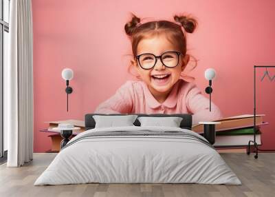 portrait of a happy child little girl with glasses sitting on a stack of books and reading a books, light pink background. Wall mural