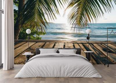 Weathered wooden planks provide a natural foreground to a soft-focus tropical beach scene, with palm fronds framing the dazzling turquoise sea Wall mural