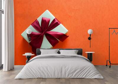 white gift box with red bow on orange background Wall mural