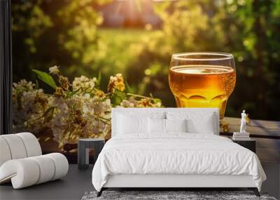 A beautifully presented glass of golden mead, surrounded by fresh honeycomb and wildflowers on a rustic wooden table in the soft glow of a summer afternoon Wall mural