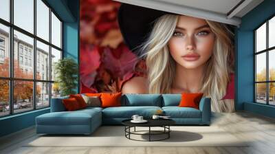 A stunning portrait of a blonde woman with a black hat, surrounded by vibrant red autumn leaves, creating a beautiful and seasonal atmosphere Wall mural