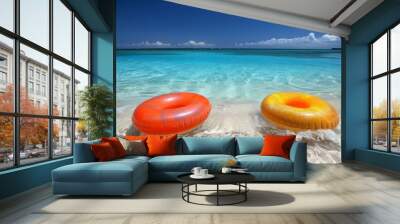 Two vibrant colored inflatable swim rings gently floating on the crystal-clear turquoise waters of a picturesque tropical beach Wall mural