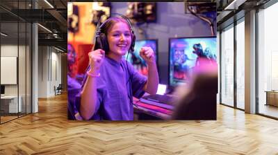 Portrait of young gamer girl playing online video games celebrating that she is winning the game Wall mural