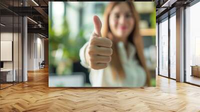 businesswoman showing thumbs up gesture in a office blur background Wall mural