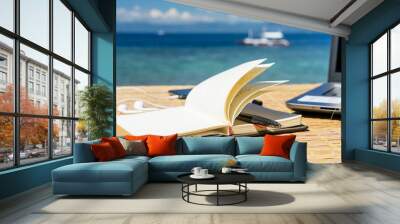 Opened empty notepad is on the table with phone and headphones at the tropical sea background Wall mural