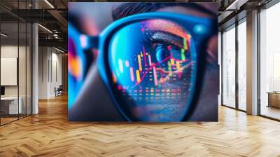 A close-up view of a person's eyes framed by a pair of glasses, reflecting stock market charts, focusing on the analysis of financial data. Wall mural