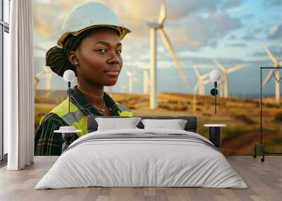 A female engineer stands confidently in front of wind turbines at a wind farm, showcasing her commitment to renewable energy. Wall mural