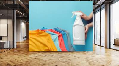 A white laundry detergent bottle, next to it there are hands of a woman placing a folded shirt. Wall mural