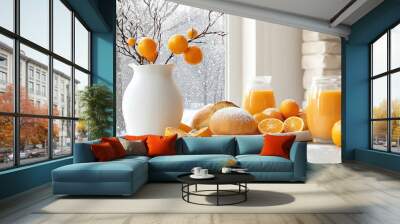 A cozy winter breakfast with fresh orange juice, oranges, and bread on a white table near a snowy window. Wall mural