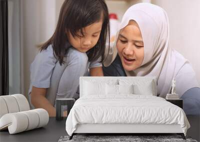 Asian muslim mother drawing with her daughter, single mom teaching baby girl, learning on the floor, happy family Wall mural