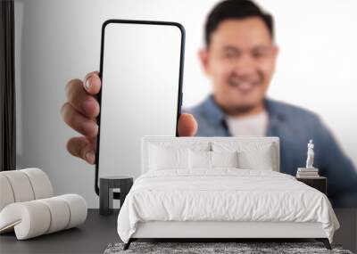 Portrait of young young Asian man presenting smart phone mockup with happy cheerful expression Wall mural