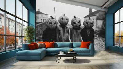 black and white vintage photo of horror, four kids wearing halloween pumpkin masks in a street, small church in the background. Wall mural