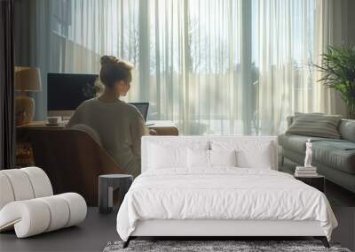 mother sitting at a desk in the living room working from home on a laptop, baby playing on the floor in the background,  Wall mural