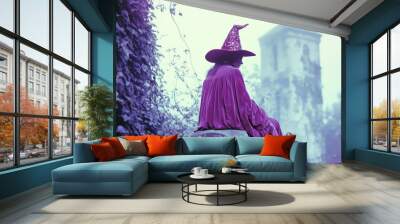 Vintage film still of a witch in a pink fuchsia velvet dress and hat, sitting on a tombstone in a foggy graveyard. Wall mural