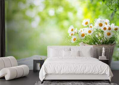  A cup of tea and a small basket with daisies on the table against a green spring background.  Wall mural