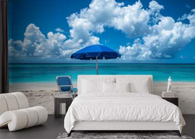 A beach scene with two blue lounge chairs and a umbrella. The chairs are facing the ocean and the umbrella is providing shade.
 Wall mural