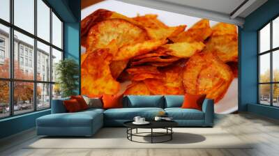 Dried and fried cassava slices mixed with spicy chili sauce place on white plate isolated on wood texture background. This is local Malaysian traditional junk food also call as Kerepek Ubi.    Wall mural