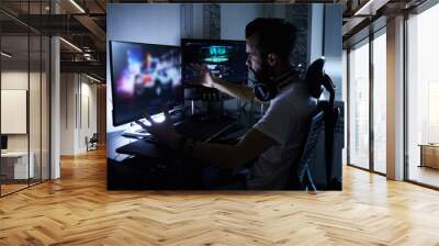 a young 30-year-old gamer is sitting at a computer, playing computer games, nervous, angry, worried.selective focus with low depth of focus Wall mural