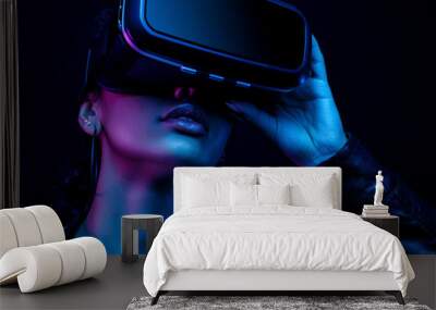 Young african american girl playing game using VR glasses, enjoying 360 degree virtual reality headset for gaming, isolated on black background in neon light Wall mural