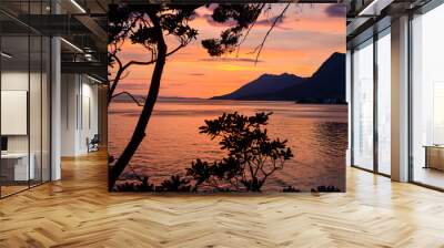 Beautiful orange sunset at the sea. Silhouette of mountains in distance.  Wall mural