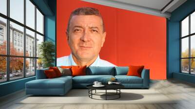 close up portrait of an elegant senior man brown eyed and with grey hair isolated on red background Wall mural