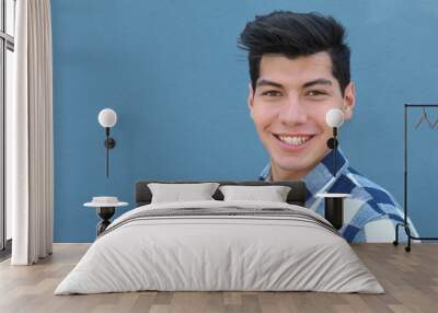 handsome hispanic man with a perfect white smile isolated on a blue background with copy space Wall mural