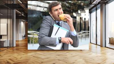 Overworked businessman eating fast food on the go Wall mural