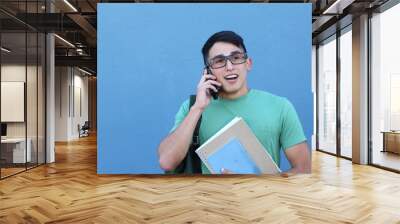 Surprised shocked student talking on mobile phone on blue background Wall mural