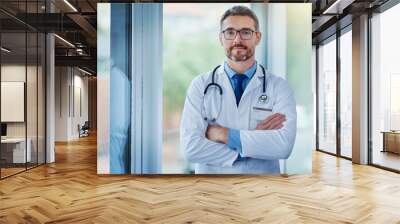 Mature man, doctor and arms crossed for portrait in hospital, medical support and cardiologist. Male person, medicine and physician at hospital for consultation service, medicare and proud medicine Wall mural