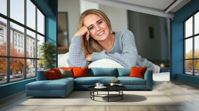 Portrait, relax and happy woman on sofa with smile in living room with home, house or apartment. Face, comfortable lady or girl on couch with peace or confidence resting on break for wellness Wall mural