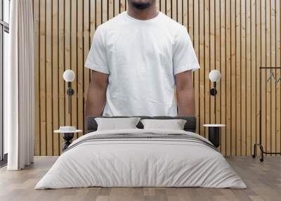 Close up of attractive dark-skinned man in white T-shirt on wooden background. Wall mural