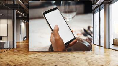 Young brunette girl holding mobile phone while waiting meal. Focus is on hands and mobile Wall mural