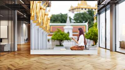 Asian buddhist woman is reading Sanskrit ancient palm leaf manuscript of Tripitaka the Lord Buddha dhamma teaching while sitting in temple on holy full moon day to chant and worship in the monastery Wall mural