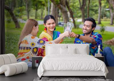 Group of transgender and homosexual people cheers and celebrating LGBTQ+ pride month in colorful dress and rainbow flag while picnic in the park Wall mural