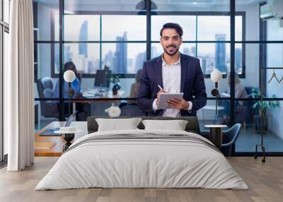 Portrait of Caucasian business man CEO is standing in the office at table with digital tablet and showing statistic chart showing annual report and skyscraper background Wall mural