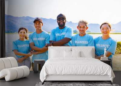 Team of young and diversity volunteer workers group enjoy charitable social work outdoor in beach cleaning project wearing blue t-shirt while joining hand in assemble unity concept Wall mural