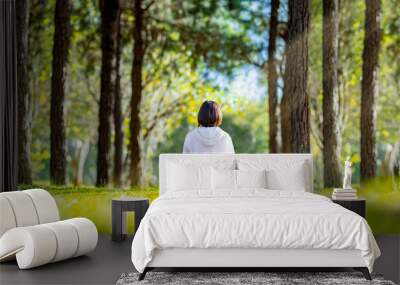 Woman relaxingly practicing meditation in the pine forest to attain happiness from inner peace wisdom with beam of sun light for healthy mind and soul concept for healthy mind and soul Wall mural