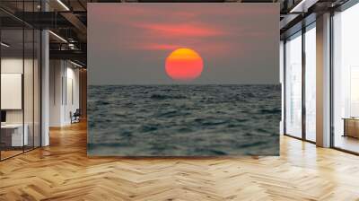 The sun is falling into the sea, the bottom of the sun eccentric because the refraction of the atmosphere. , The sky is orange And the sea is dark Wall mural