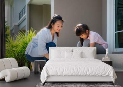 Asian mother help her daughter primary students in uniform to wearing their shoelace of shoes infront of home in the morning school routine for day in the life getting ready for school. Wall mural